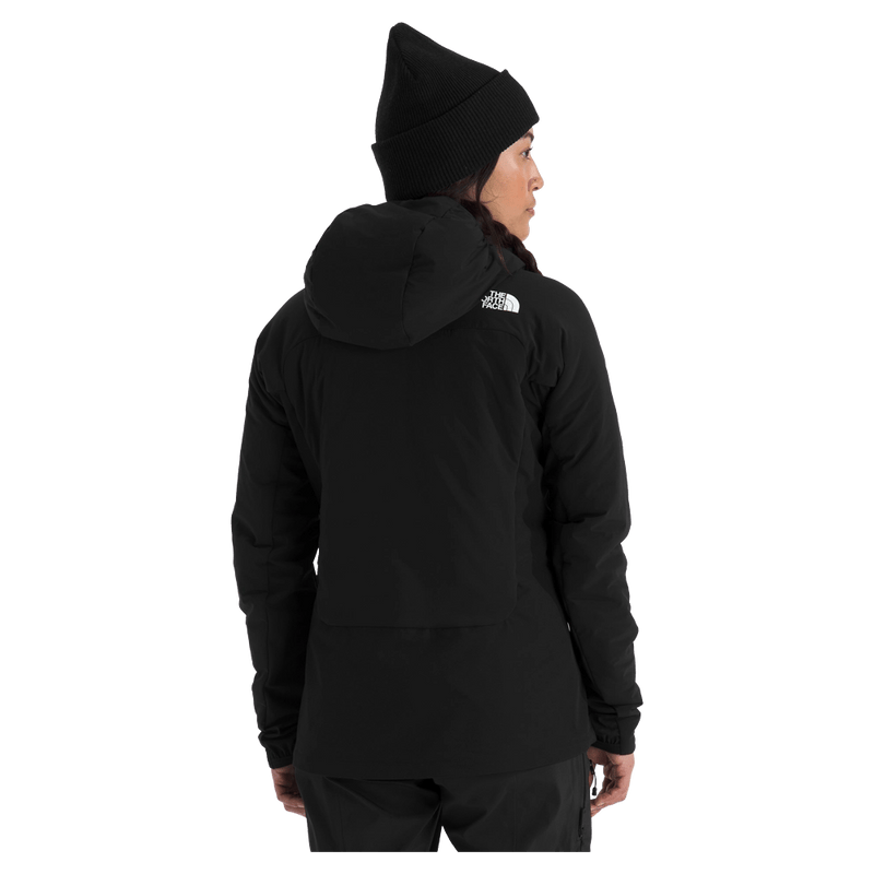 View of a woman wearing The North Face Summit Casaval Hybrid Hoodie in black, showing the back side with a hood and small white logo on the left shoulder.