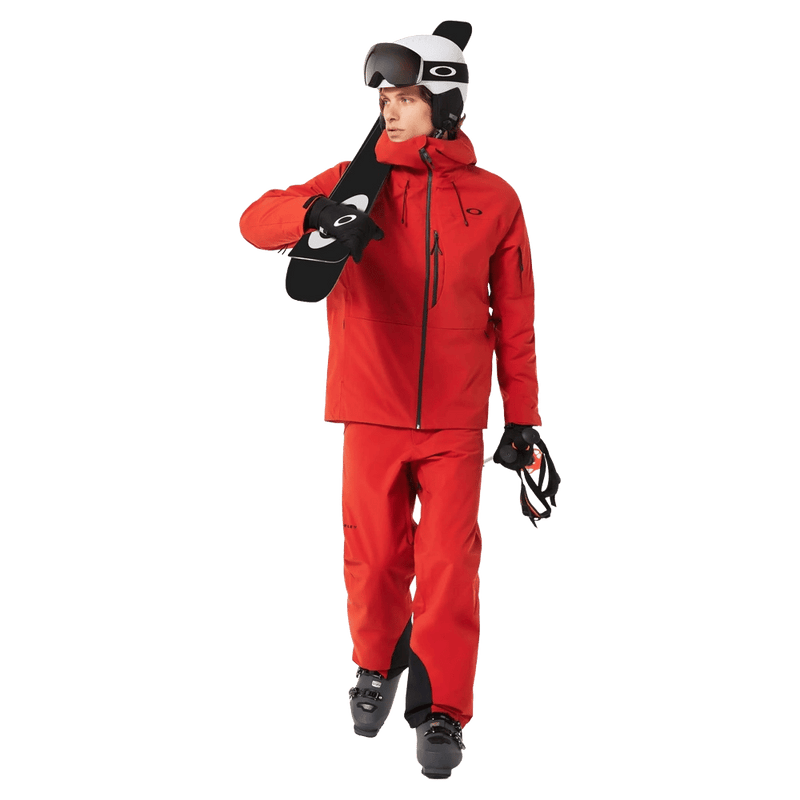 Full-body view of the Oakley Canopy Insulated Ski Pants in HIBISCUS RED colourway, men's model