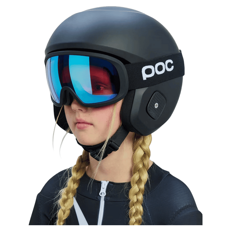 Matte black Poc Skull Dura Jr kids ski helmet with blue mirrored goggles worn by a child with blonde braids.