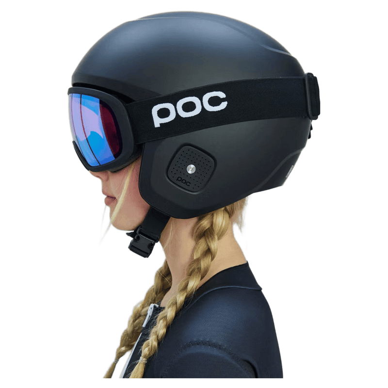 Side profile of a child wearing a matte black Poc Skull Dura Jr kids helmet and blue iridescent goggles.