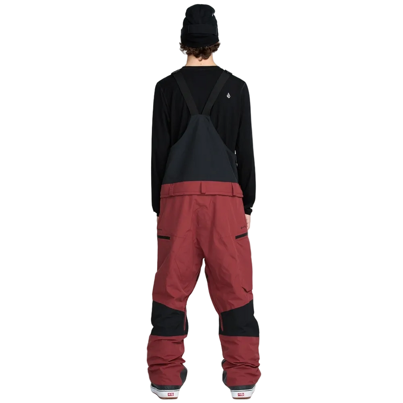 Rear, on-body image of the Rain Gore-Tex Bib Snowboard Pants from Volcom in Burnt Red. Featuring belt loops, Zip Tech pant to jacket interface, side pockets with zip closure and contrast black through upper bib and behind knees.
