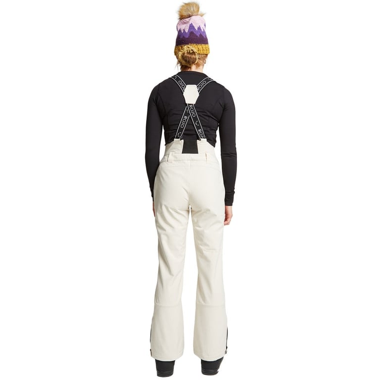 Rear view of Rojo women's off-white high-rise softshell ski pants with black branded suspenders and slim legs.