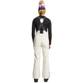 Rear view of Rojo women's off-white high-rise softshell ski pants with black branded suspenders and slim legs.