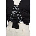 Rear view of cream Rojo high-rise ski pants with black X-back suspenders featuring white logo branding.