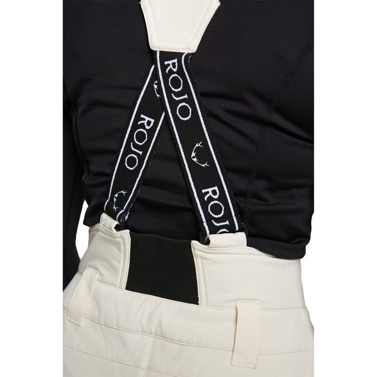 Rear view of cream Rojo high-rise ski pants with black X-back suspenders featuring white logo branding.