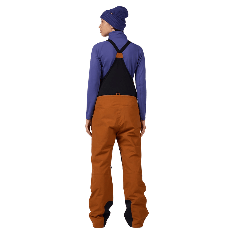 Back view of the Rossignol Outerlimits Insulated Bib in DEEP CARAMEL colourway, women model