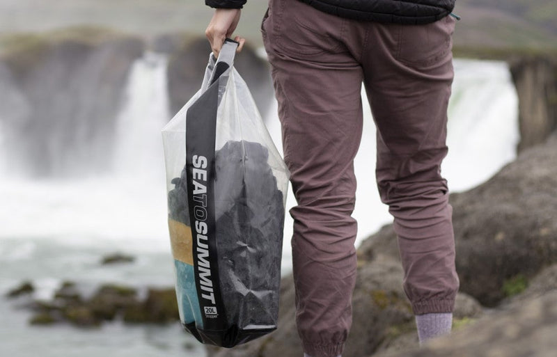 Model holding Sea To Summit Stopper Clear Dry Bag with articles inside