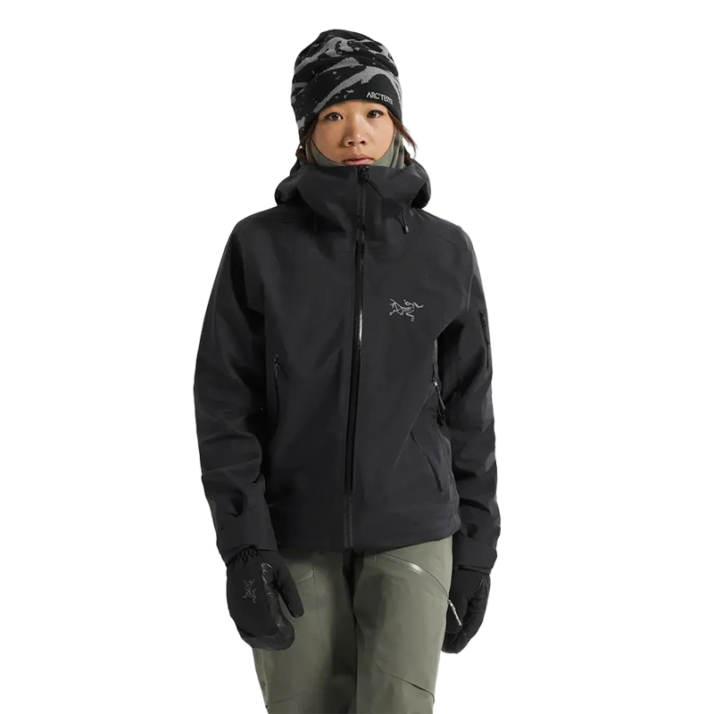 Front view of a woman wearing the Sentinel Ski Jacket in Black featuring a full zip front and silver grey embroidered logo on the chest. 