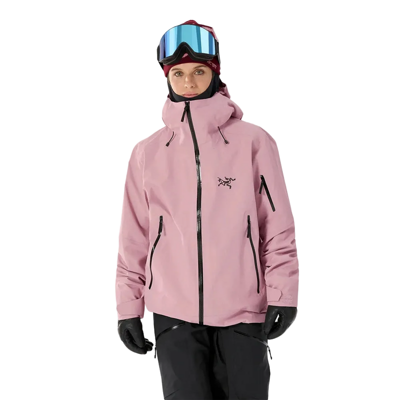 Front view of a woman wearing the Sentinel Ski Jacket in Bliss Black featuring a blush pink tone with contrast black hardwear and brand image on the chest. 