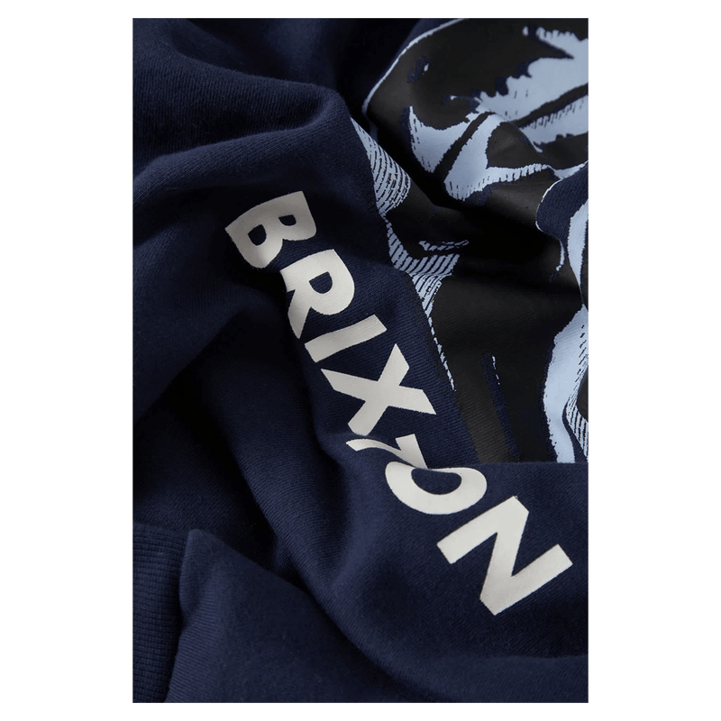 Close-up of navy blue Brixton hoodie fabric with white vertical branding and a light blue graphic print.