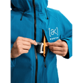 Blue Burton AK Upshift jacket with a zippered chest pocket, orange lining, and white logo.
