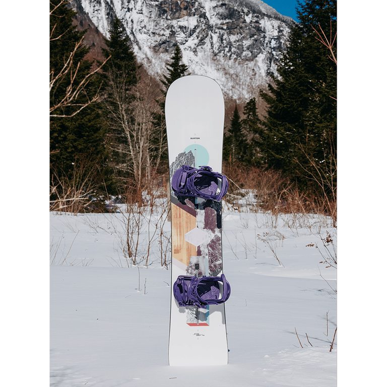 Burton Hideaway Womens Snowboard with purple bindings and mountain graphics standing in a snowy landscape.