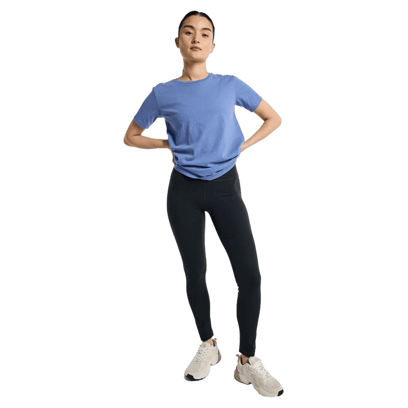 Woman wearing dark grey Burton MP Active Leggings, a blue t-shirt, and white sneakers against a black background.