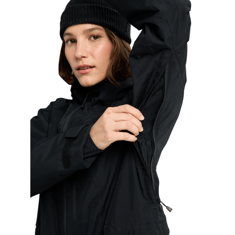 Woman in a black Burton Reserve Insulated Snowboard Jacket demonstrating the underarm ventilation zipper.