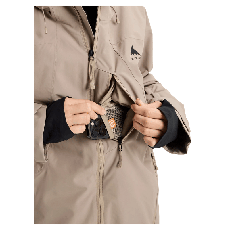 Tan Burton Reserve women's snowboard jacket showing a zippered chest pocket with a phone and black wrist gaiters.