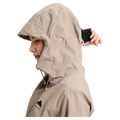Side profile of a woman wearing a beige Burton Reserve Insulated Snowboard Jacket with the hood up and chest logo.