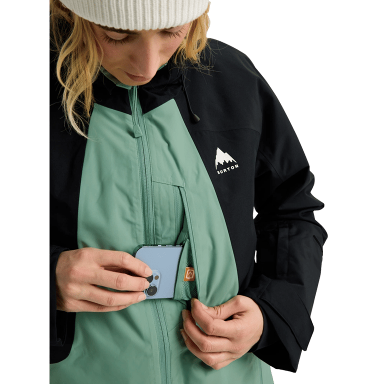 Black and green Burton Reserve Insulated Snowboard Jacket with a phone being placed in a zippered chest pocket.