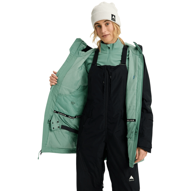 Woman wearing a black Burton Reserve Insulated Snowboard Jacket open to show mint green lining and interior powder skirt.