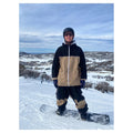 CHECKtheFeed VX Daily Snowboard Jacket in black and tan with white zipper, worn by a snowboarder on a snowy mountain.