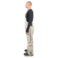 Side profile of beige Endeavor 3L Shelter Bib Snowboard Pants with black side zippers and branded suspender straps.