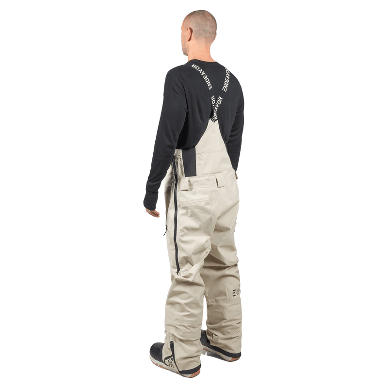 Rear view of beige Endeavor 3L Shelter Bib Snowboard Pants with branded black suspenders and side leg zippers.
