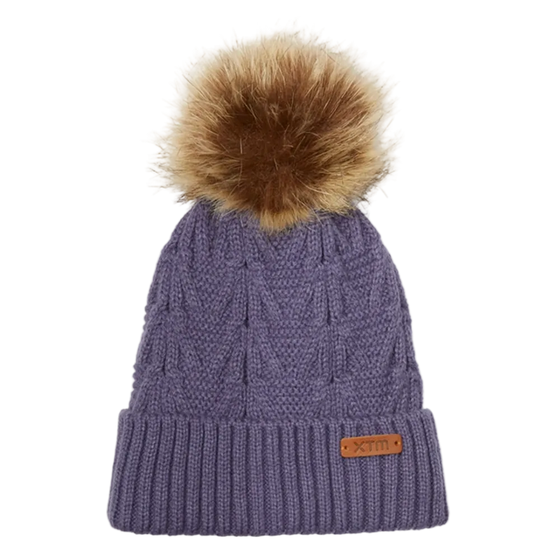 View of the Isla Beanie in Light Dusk. Featuriing a cable knit design with ribbed fold up hem, leather brand tag and brown fur pom pom. 