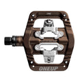 Bronze One Up Components clip-in mountain bike pedal with silver metal mechanism and threaded spindle.