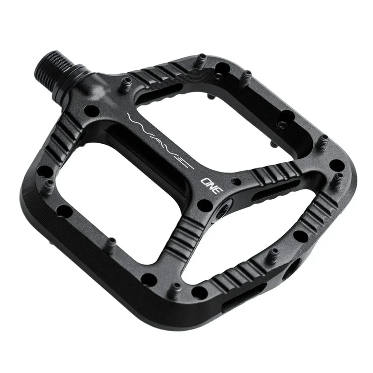 One Up Components Wave black flat mountain bike pedal with metal pins, textured surface, and white branding.