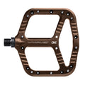 Bronze One Up Components Wave flat pedal with a scalloped platform design and silver traction pins.