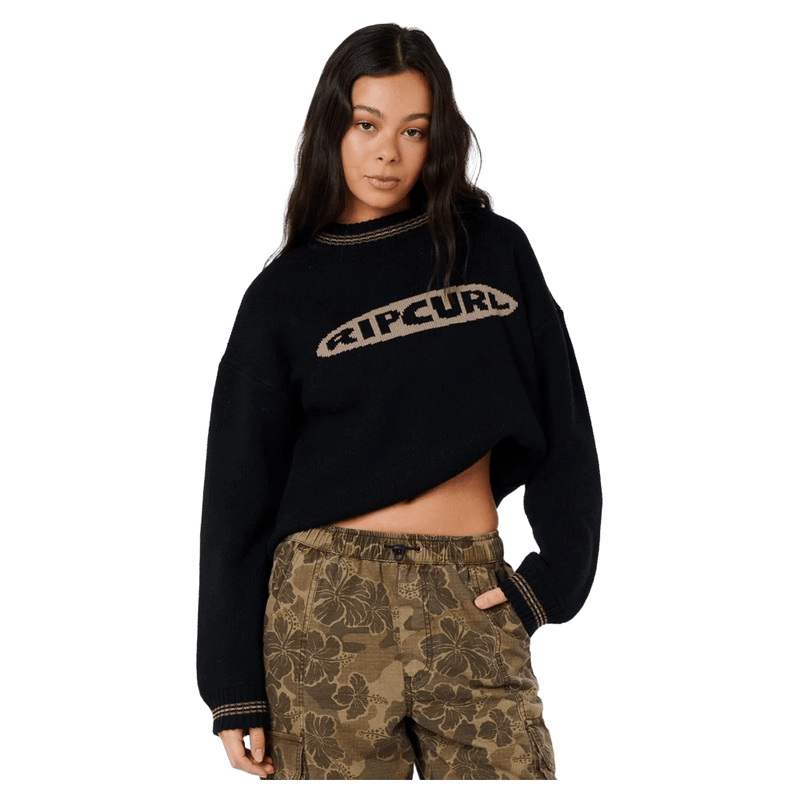Black Rip Curl Half Moon Bay sweater with tan logo and olive green floral camo cargo pants.