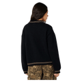 Back view of a woman in a black Rip Curl Half Moon Bay sweater with tan striped trim on the collar, hem, and cuffs.