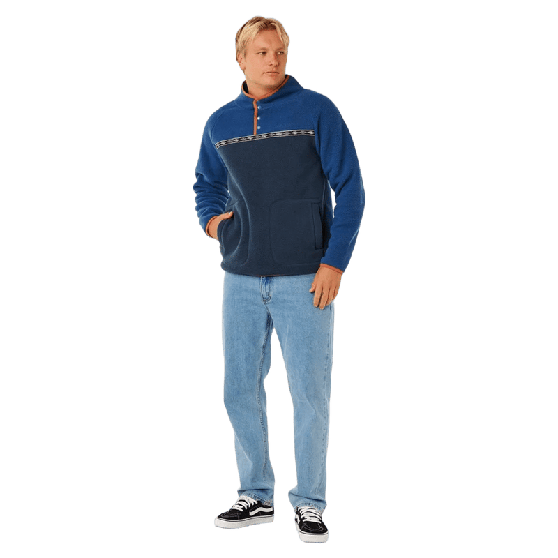 Rip Curl Heritage Polar Fleece in navy and blue with a patterned chest stripe and snap collar, worn with light jeans.