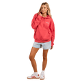 Woman wearing a coral pink Rip Curl Ocean Break Heritage Hoodie with a kangaroo pocket and white chest logo.