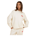 Woman wearing a cream Rip Curl Surf Puff Inspired Crew sweatshirt with a small red chest logo and matching track pants.