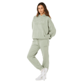 Woman wearing light green Rip Curl Varsity Sports track pants and matching hoodie with white sneakers.