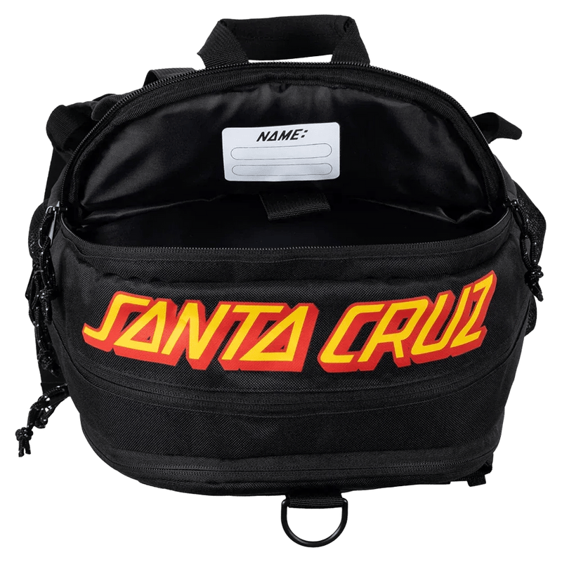 Top view of an open black Santa Cruz kids backpack with a yellow logo and interior name tag.
