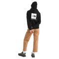 Rear view of a woman wearing The North Face Evolution Box NSE Hoodie for Women in Black featuring a box logo graphic in white and black.