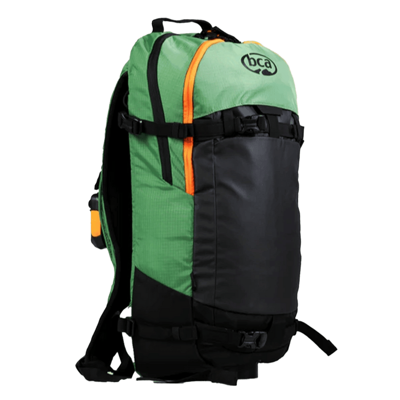 Side view of the Stash 20L Backpack from BCA in green, featuring a green upper and sides with a black front, top carry handle, adjustable buckles at the upper and lower sections, and an orange top front zip.