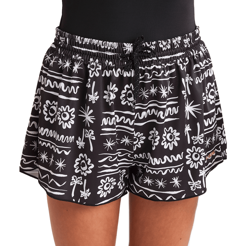 Cropped view of a girl wearing the Lost On You Swim Volley - Kids from Billabong in Black. Featuring a gathered elastic waist with drawstring and a mixed abstract print in white, with gold embroidered branding on the lower left hem
