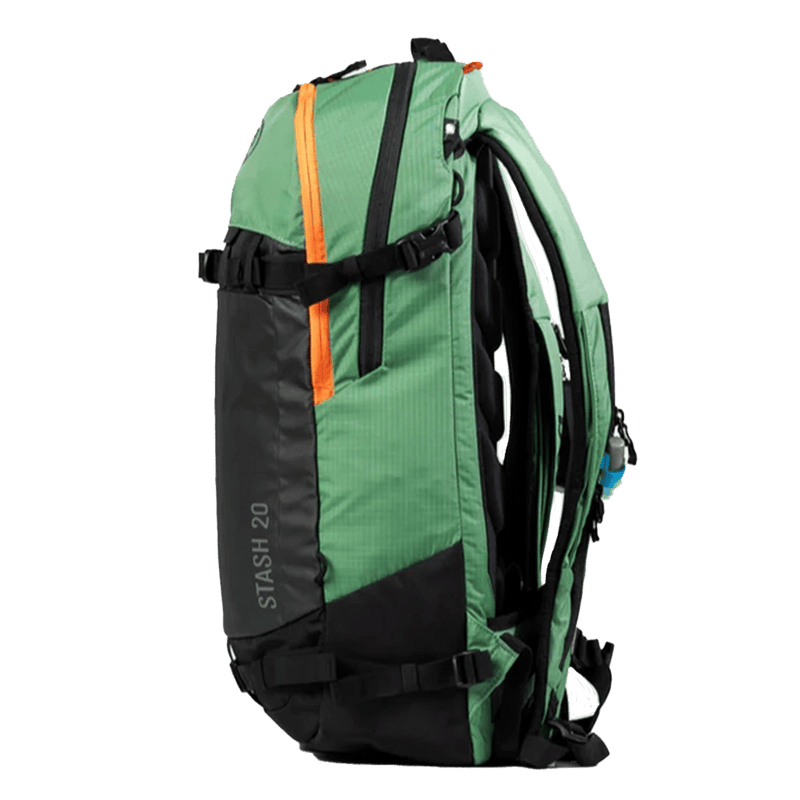 Side view of the Stash 20L Backpack from BCA in green, featuring a green upper and sides with a black front, top carry handle, adjustable buckles at the upper and lower sections, orange top front zip, and adjustable padded dual zippered shoulder straps with hydration channel.