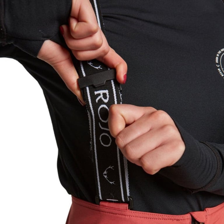 Close-up of adjustable black and white Rojo branded suspenders on pink softshell high rise ski pants.